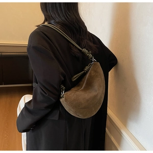 Detail of tan suede half-moon bag with olive green knotted strap and metallic rings