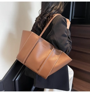 Detail of dark brown tote bag with contrast stitching and embossed fashion lettering