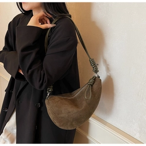 Detail of dark brown suede crescent bag featuring leather knot strap and metal zipper closure