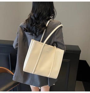 Creamy leather tote bag with FASHION lettering shown on a model in a modern office