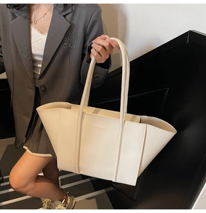 Detailed view of creamy white tote bag featuring FASHION print and long shoulder straps