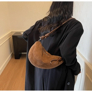 Detailed side view of a brown suede moon bag with a decorative knotted shoulder strap