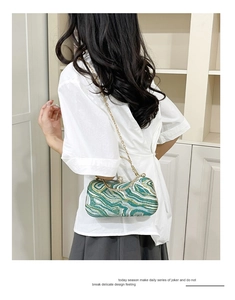 Macro view of green marble texture evening bag with rhinestone clasp and gold chain
