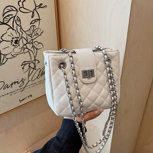 White quilted rhombic chain bag with silver hardware held by a model in a French style setting