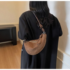 Detail showing the brown suede crescent bag with unique knot accents on the shoulder strap