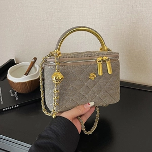 Quilted woven chain bag with gold metal handle and flower charm in earth tones