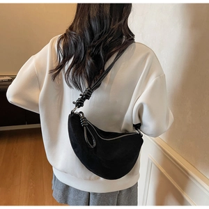 Detail of black suede crescent bag featuring a unique knotted shoulder strap design