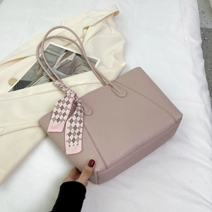 Pink lychee texture leather tote bag with a decorative silk scarf in a lifestyle setting
