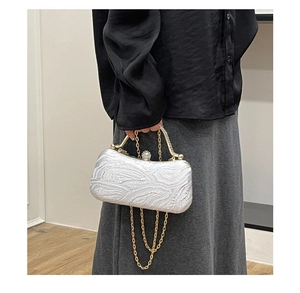 Detail of silver evening clutch with wave texture, gold frame and rhinestone clasp