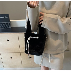 Dettaglio borsa di peluche nera con foulard floreale, perla e tracolla a catena d'oro