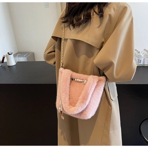 Dettaglio borsa a tracolla in peluche rosa con catena metallica e ciondolo di perle