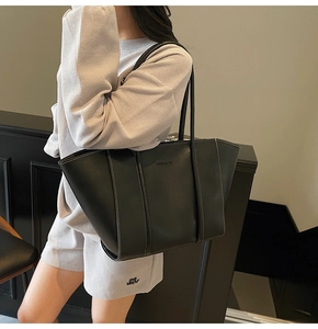 Detail of black leather tote bag featuring white contrast stitching and Fashion logo