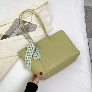 Detail of light green pebbled leather tote bag with stylish checkered silk scarf handle