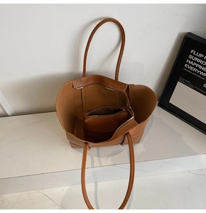 Detail view of caramel brown tote bag with leather texture and matching inner pouch