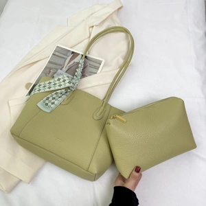 Close-up of light green lychee leather tote with matching pouch and plaid silk scarf