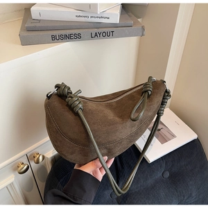 Detailed view of brown suede dumpling bag featuring a green knotted cylinder shoulder strap