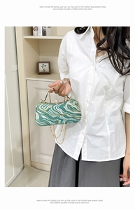 Close-up of green marble pattern evening bag with gold chain and diamond clasp detail