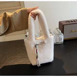 Dettaglio borsa di peluche bianca con perla, nastro stampato e catena metallica dorata