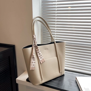 Chic beige lychee grain tote bag with decorative checkered scarf on a sunny windowsill