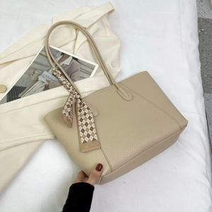 Detail of beige lychee leather tote bag featuring a decorative brown checkered silk scarf