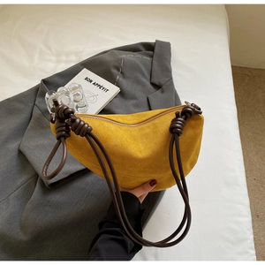 Detail view of yellow faux suede half-moon bag featuring a unique dark brown knotted strap