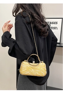 Detail of a marble textured evening bag with a gold chain strap shown on a model