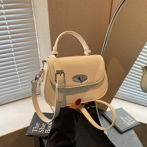 Minimalist cream saddle bag with silver clasp shown in a lifestyle interior setting