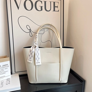 Detail view of beige lychee leather tote bag with a decorative fashion silk scarf on the handle