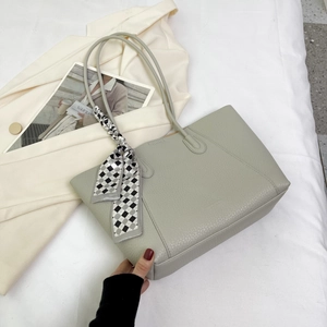 Detail of lychee pattern leather tote bag with a checkered silk scarf on the handle