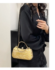 Detail of evening clutch with wave texture, rhinestone handle and gold chain strap