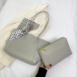 Light gray pebbled leather tote bag set with decorative scarf on white fabric background