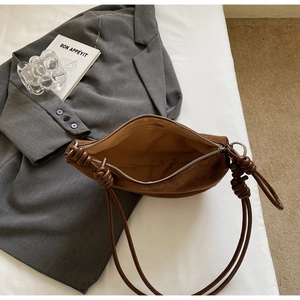 Detail view of brown suede shoulder bag showing internal zipper pocket and knot design