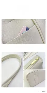 Detail view of beige lychee leather tote with gold zipper and reinforced stitching