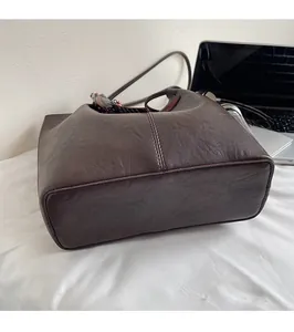 Détail du cabas en cuir marron foncé montrant la base large et le foulard en soie au manche