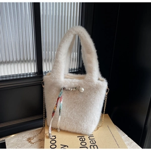 Dettaglio borsa a secchiello in peluche con perla, nastro di seta e catena d'oro