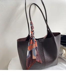 Détail d'un sac cabas marron foncé orné d'un foulard en soie imprimé géométrique à l'anse