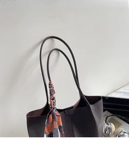 Gros plan du sac cabas en cuir marron vintage avec un foulard en soie à motifs élégant