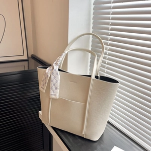 Close-up of off-white lychee grain leather tote with fashion silk scarf handle detail