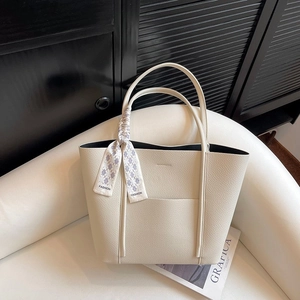 Detailed macro view of beige lychee grain leather tote bag with a decorative silk scarf