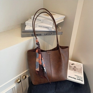 Sac fourre-tout en cuir marron avec foulard décoratif sur fond beige épuré