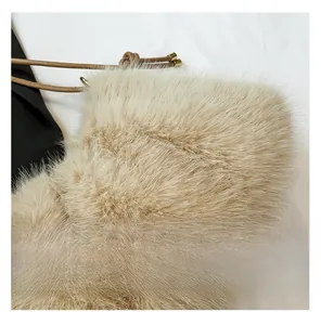 Gros plan du sac en peluche beige avec cordon marron et boucle en métal doré brillant