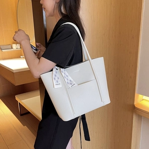 Close-up of white pebble leather tote bag with stylish blue silk scarf on handle