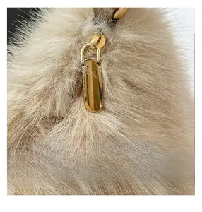 Détail de la peluche beige douce et de la fermeture éclair dorée sur le sac tendance