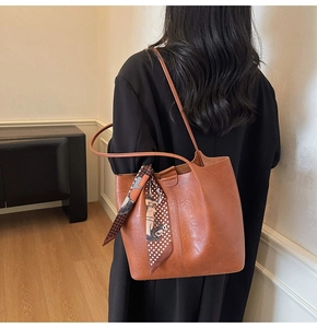 Détail d'un grand sac cabas marron avec un foulard en soie vintage noué sur la bandoulière
