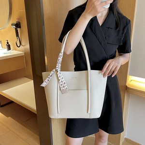 Detail of beige leather tote bag with elegant plaid silk scarf wrapped on the handle
