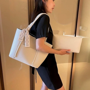 Chic off-white tote bag set with silk scarf detail worn by model on black dress