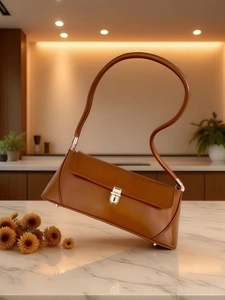 Detailed view of brown leather bag with gold buckle on marble surface in warm lighting