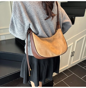 Gros plan sur le sac croissant rétro bicolore en daim kaki et cuir marron élégant