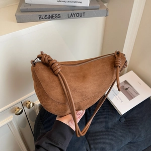 Brown suede crescent moon bag with creative knotted strap detail and minimalist design