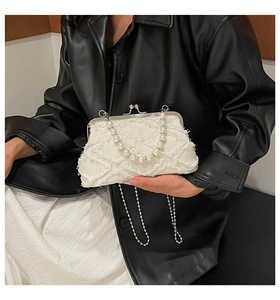 Close-up of white canvas shell bag with pearl handle and frayed edge detail